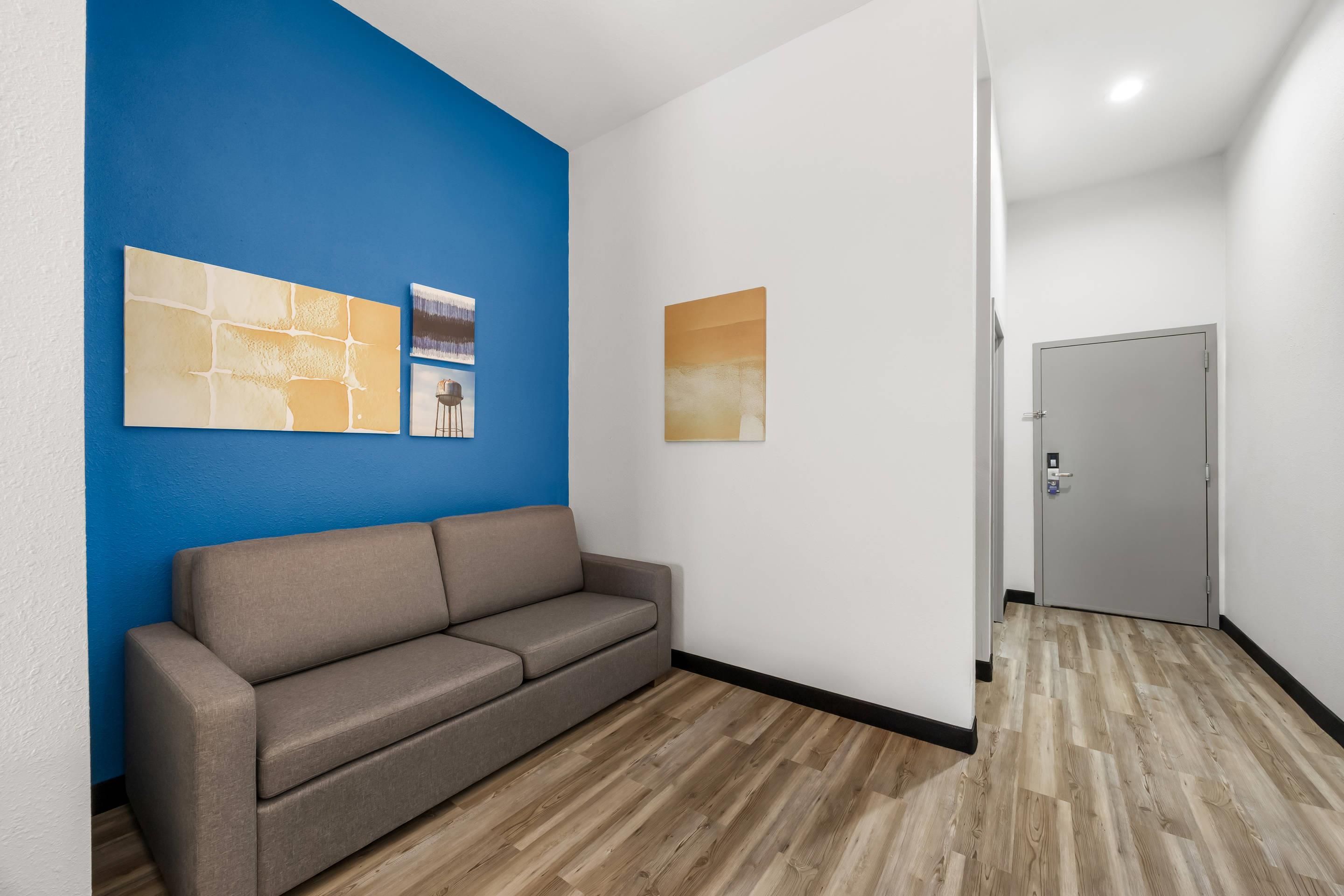 Un pasillo con un sofá marrón, una pared de acento azul y obras de arte.