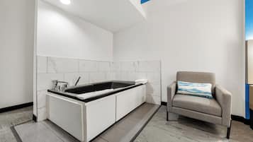 A modern bathroom with a built-in sink, a towel, and a chair with a pillow.