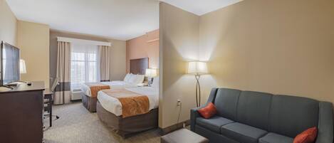 Habitación de hotel con dos camas, un escritorio, un sofá y una lámpara.