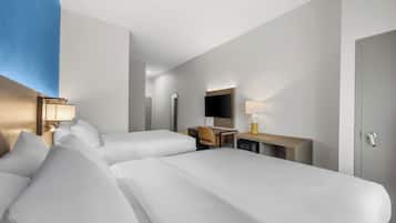 Habitación de hotel con dos camas, un escritorio, una silla, un televisor y un armario.
