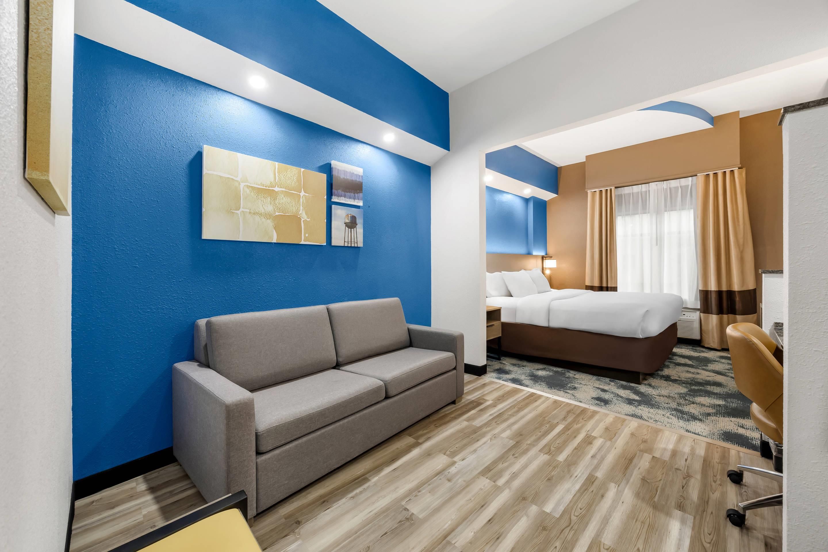 A hotel room with a sofa, a bed, a desk, and a chair.