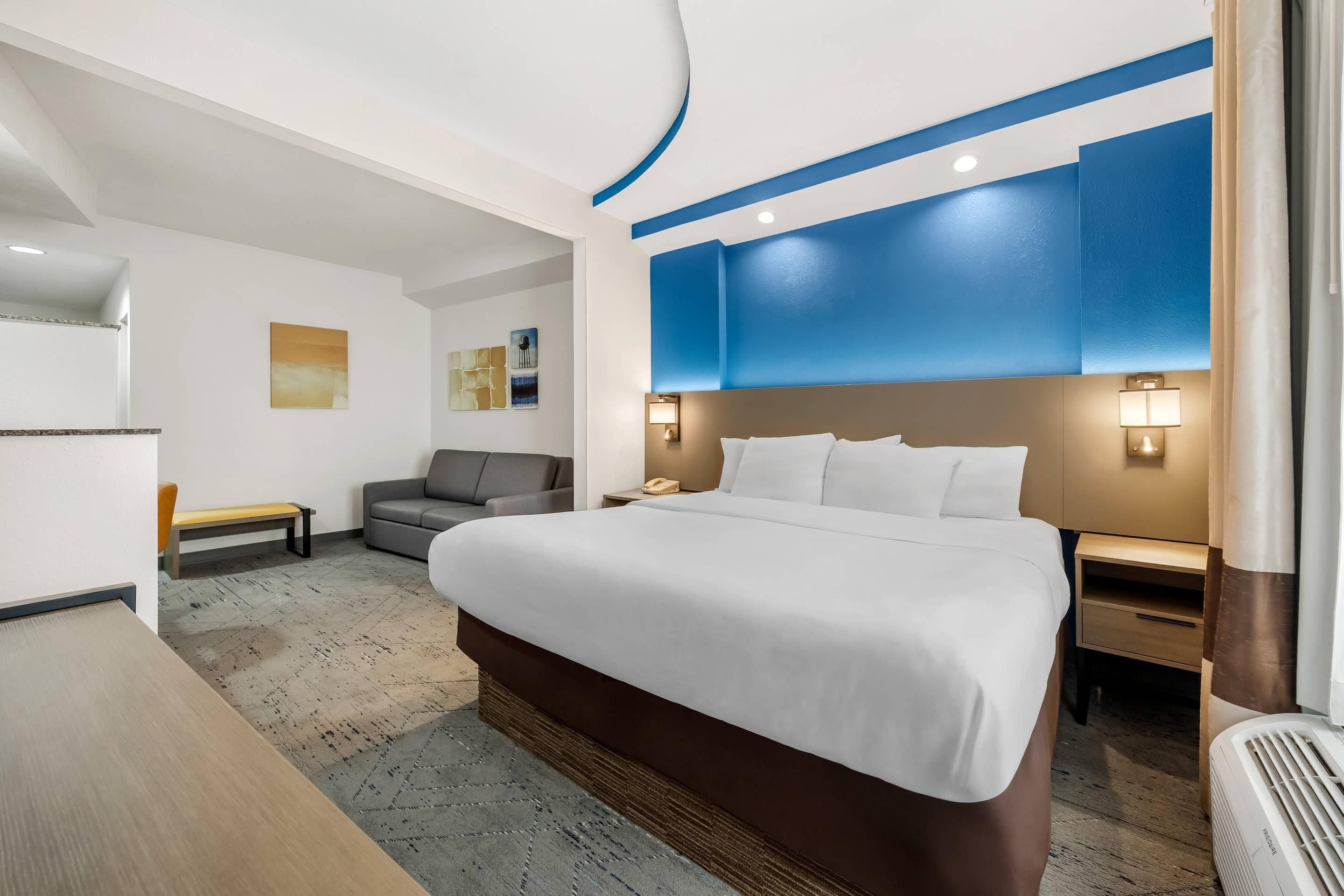 Ein Hotelzimmer mit einem grossen Bett, einem Schreibtisch, einem Sessel und einer Couch.
