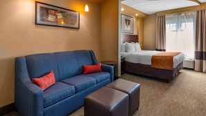A hotel room with a blue sofa, a bed with a brown headboard, and a small table.