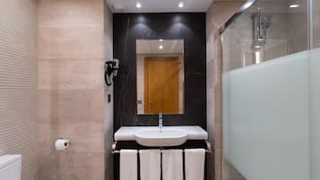 Un baño moderno con lavamanos de mármol, puerta de madera y cabina de ducha de vidrio.