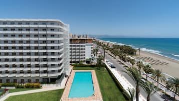 Una piscina al aire libre, sombrillas, sillones reclinables de piscina