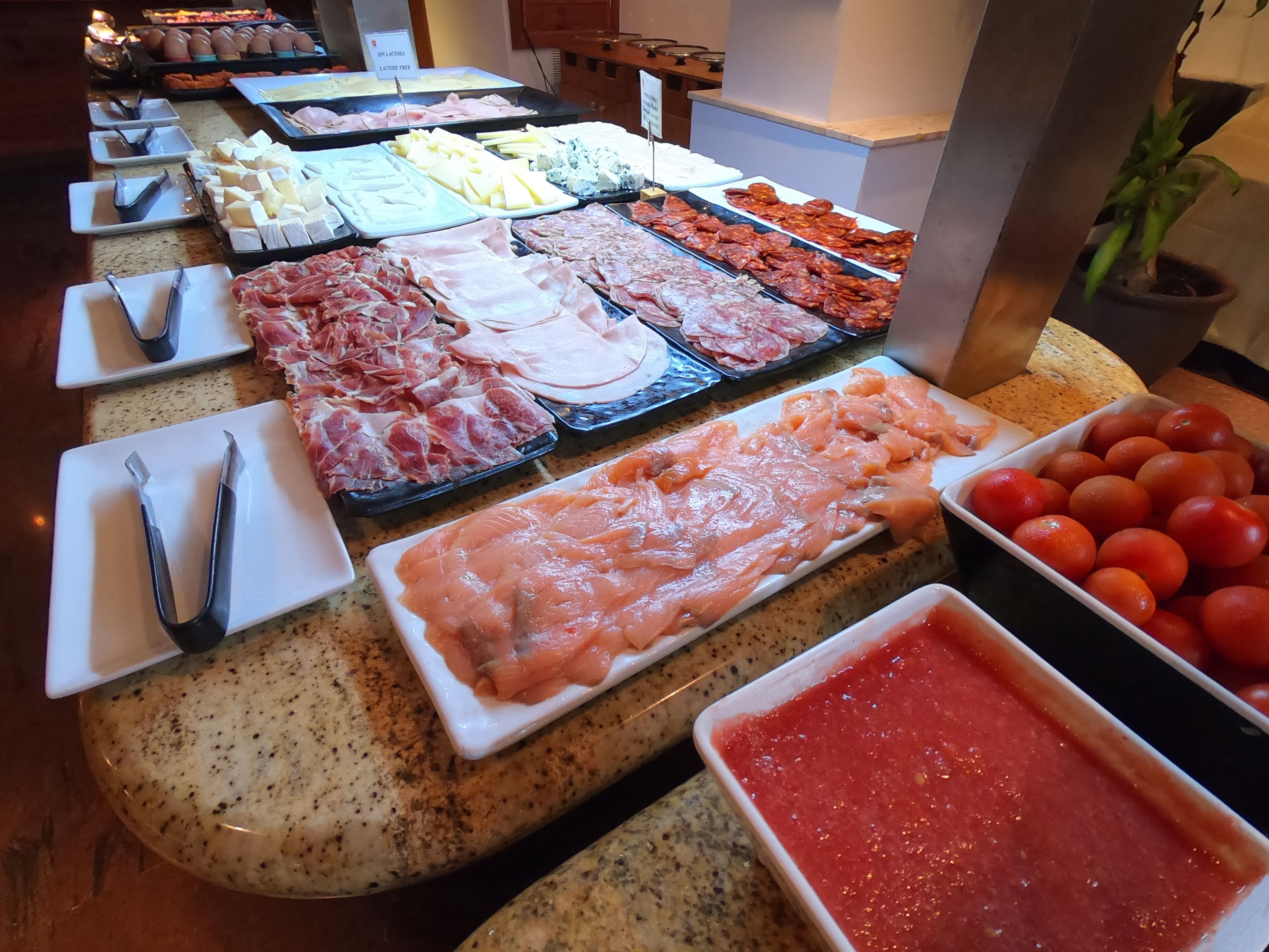 A buffet with various meats, cheeses, and tomatoes.
