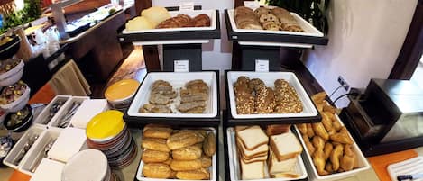 A buffet with various food items including bread, pastries, and sandwiches.