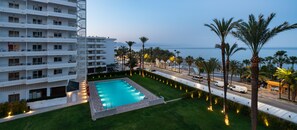 A hotel with a swimming pool, palm trees, and a view of the sea. - Hotel Apartamentos Bajondillo (Torremolinos)
