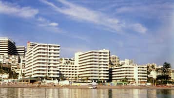 A coastal cityscape with high-rise buildings, a beach, and a calm sea.