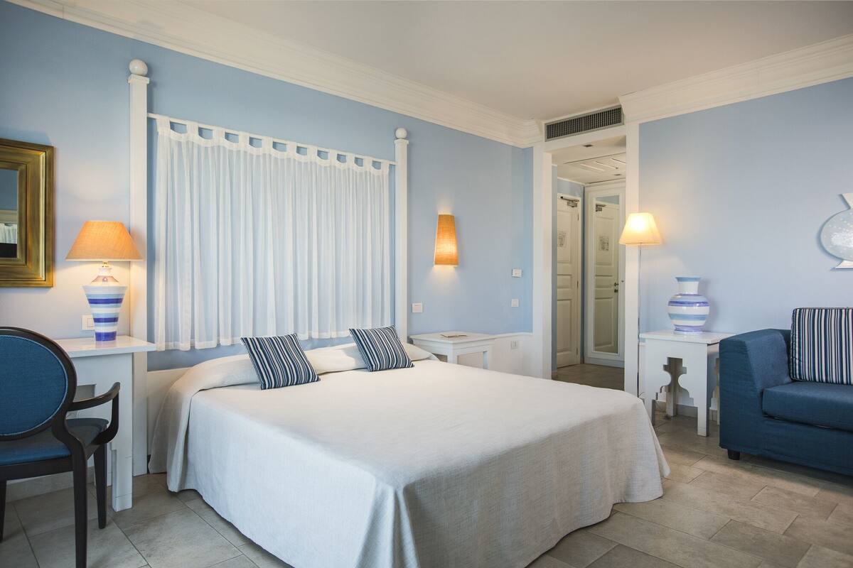 Ein Hotelzimmer mit einem großen Bett, zwei Nachttischen, einem Sessel und einem Sofa.