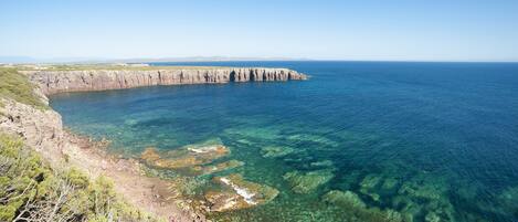 A coastal landscape with cliffs and clear blue water.