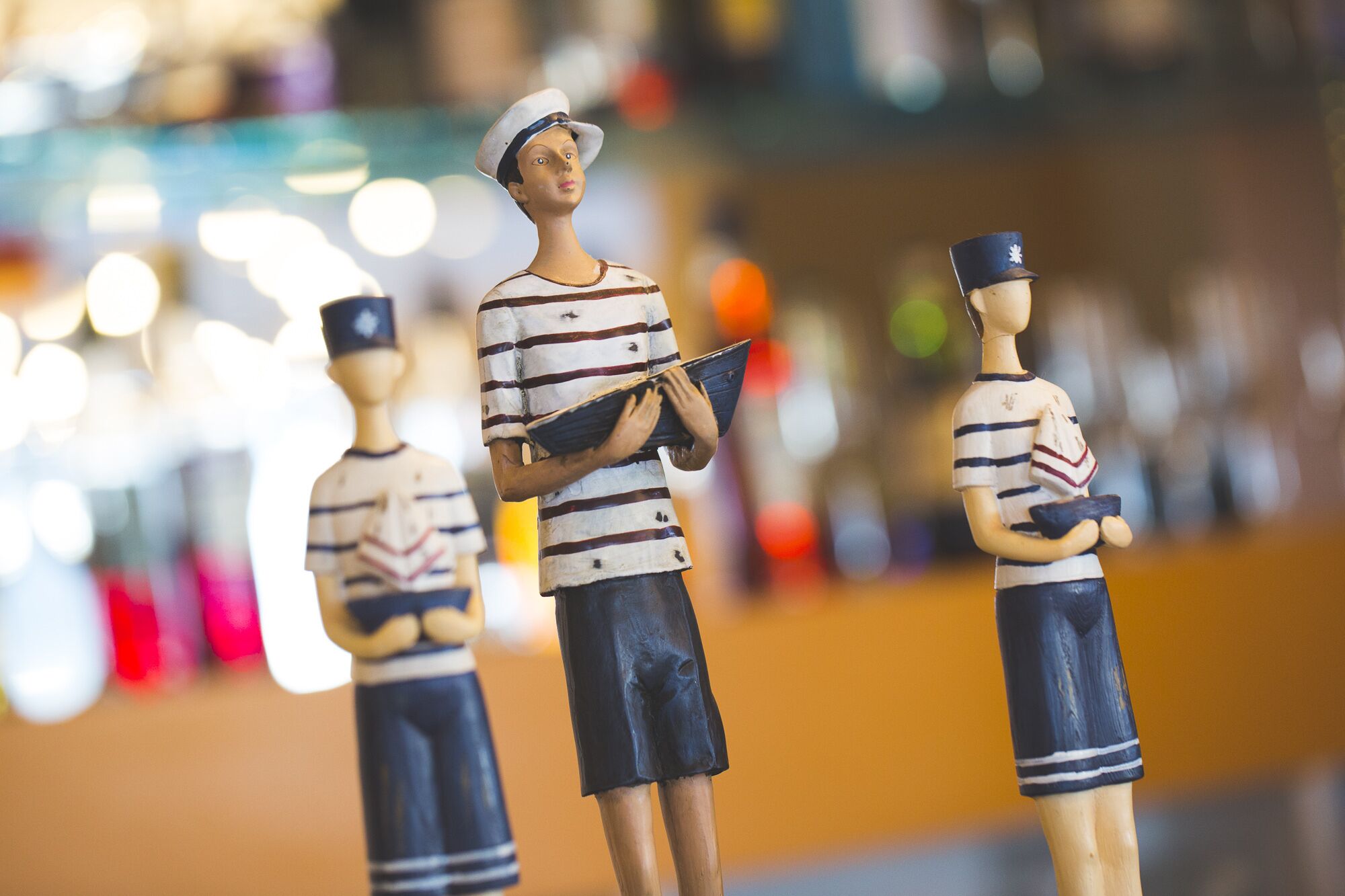 Tre träfigurer med randiga kläder och hattar, stående på en yta.