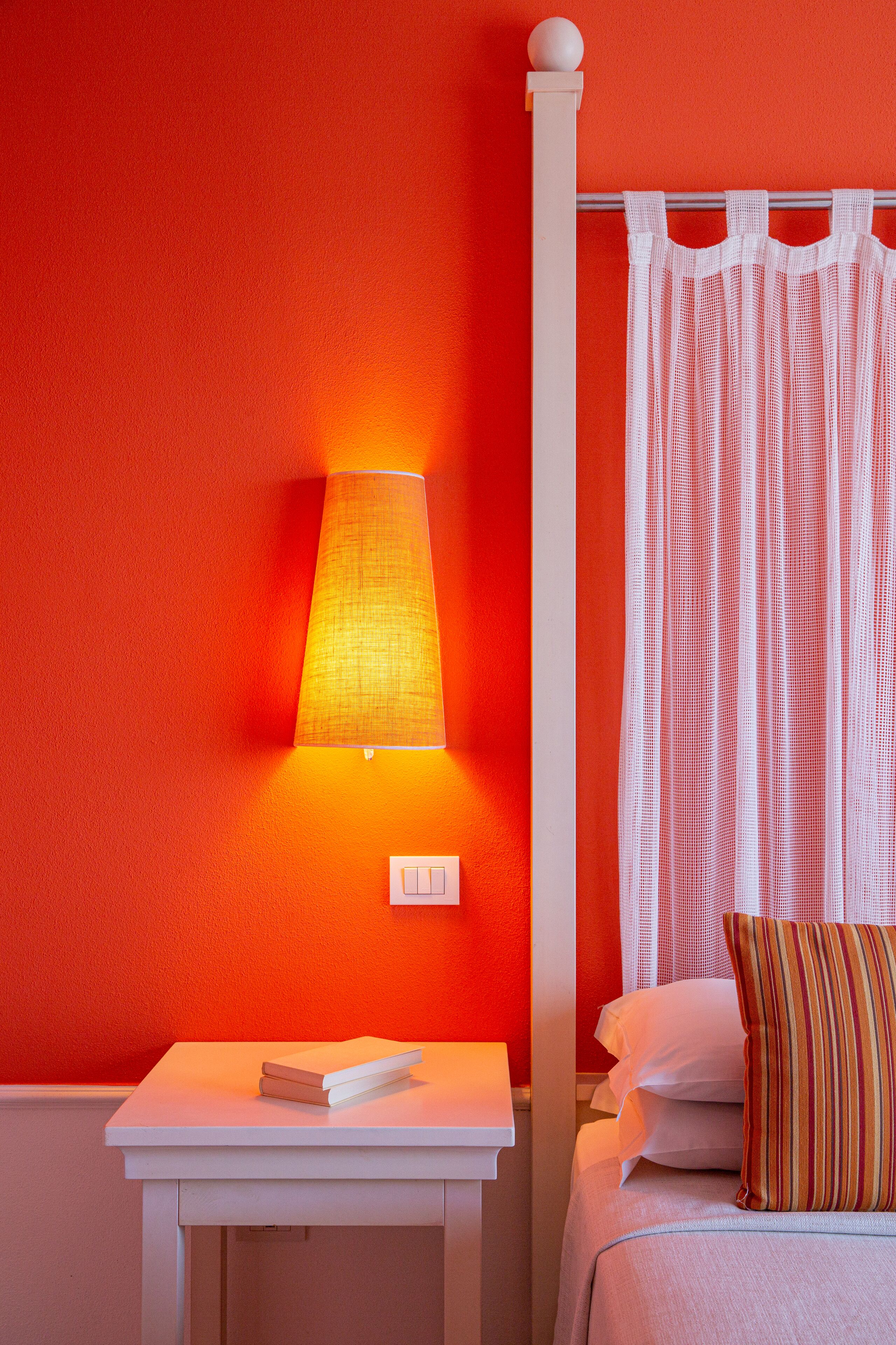 Une pièce comprenant un lit, une table de chevet, une lampe et un rideau.
