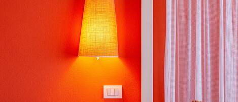 A room with a bed, a nightstand, a lamp, and a curtain.