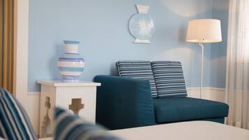 Un dormitorio con una cama, una mesita de noche con un jarrón, una lámpara y una pared decorada con un plato.