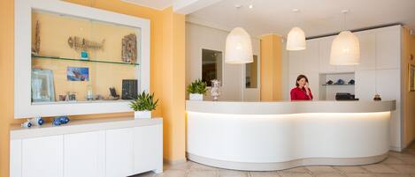 A reception area with a curved white counter, a large mirror, and pendant lighting.