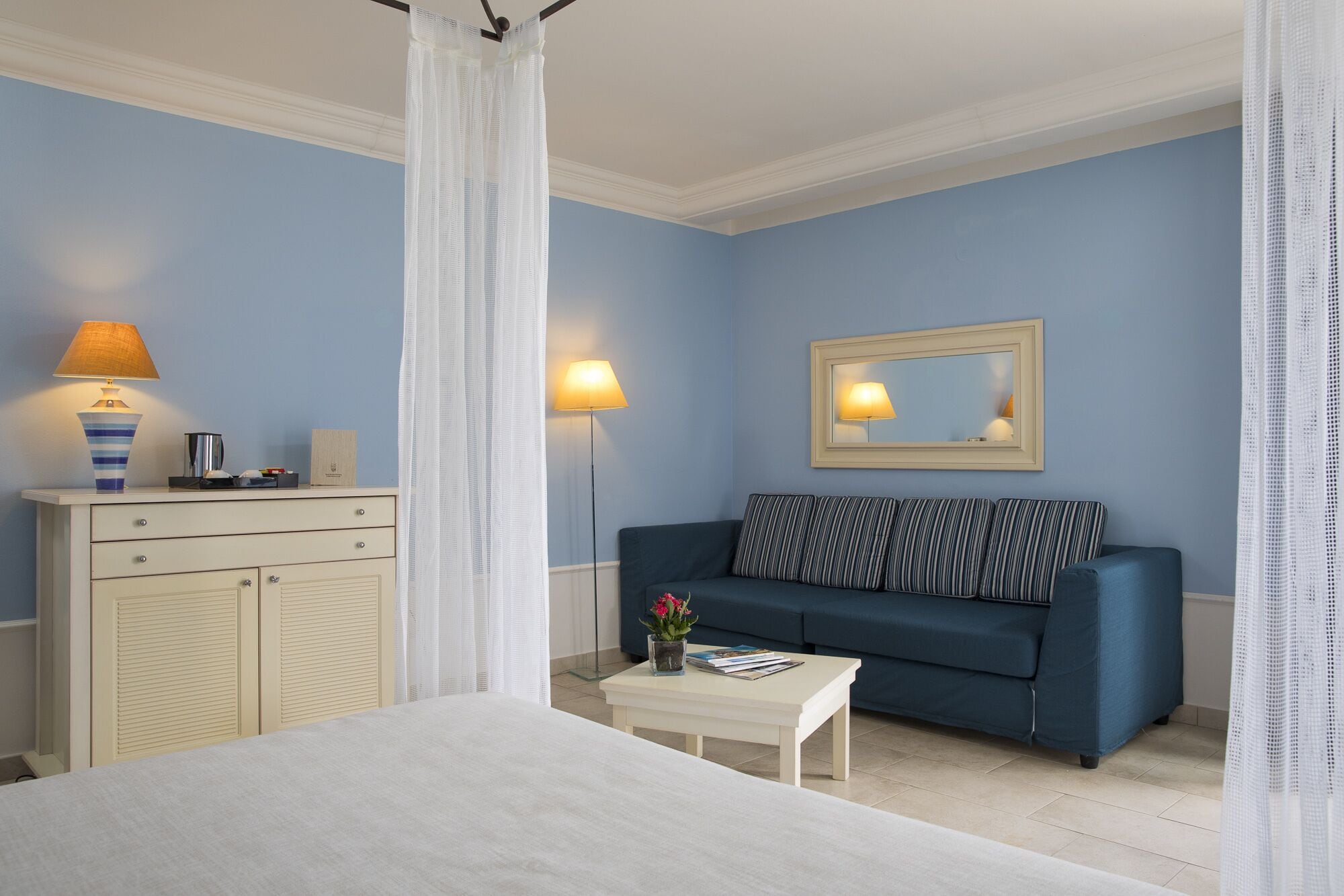 A bedroom with a bed, a nightstand, a dresser, a sofa, and a small table.