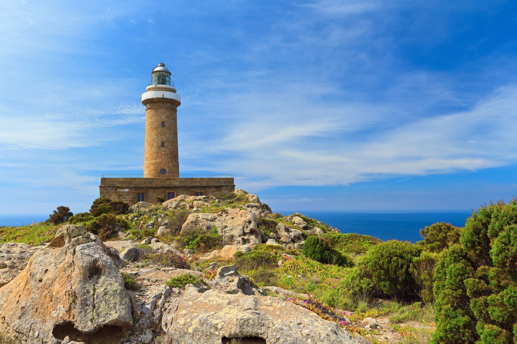 A lighthouse on a rocky outcrop with a clear view of the sea.
