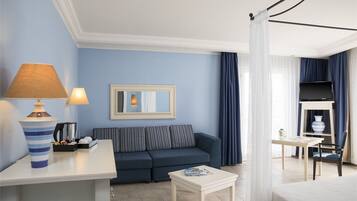 A hotel room with a sofa, a small table, a lamp, a mirror, and a television.