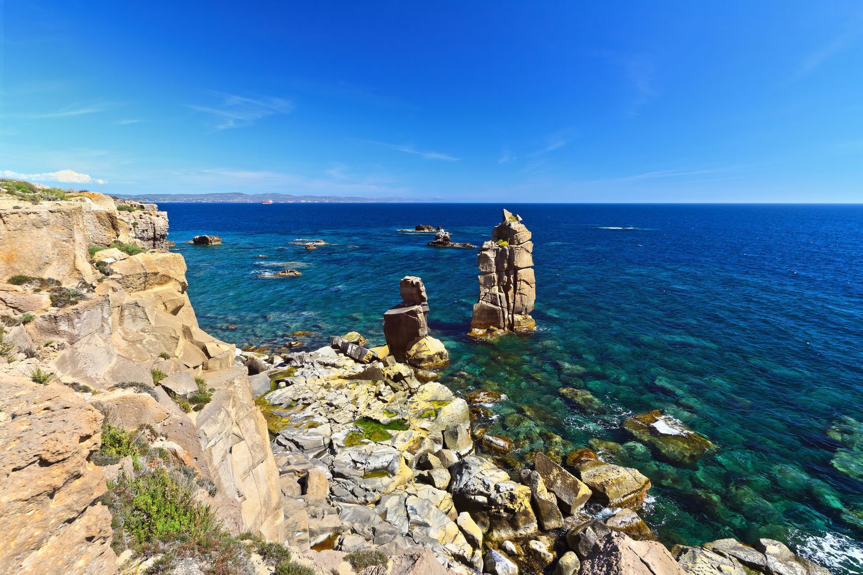 A coastal landscape with rocky formations and clear blue sea.