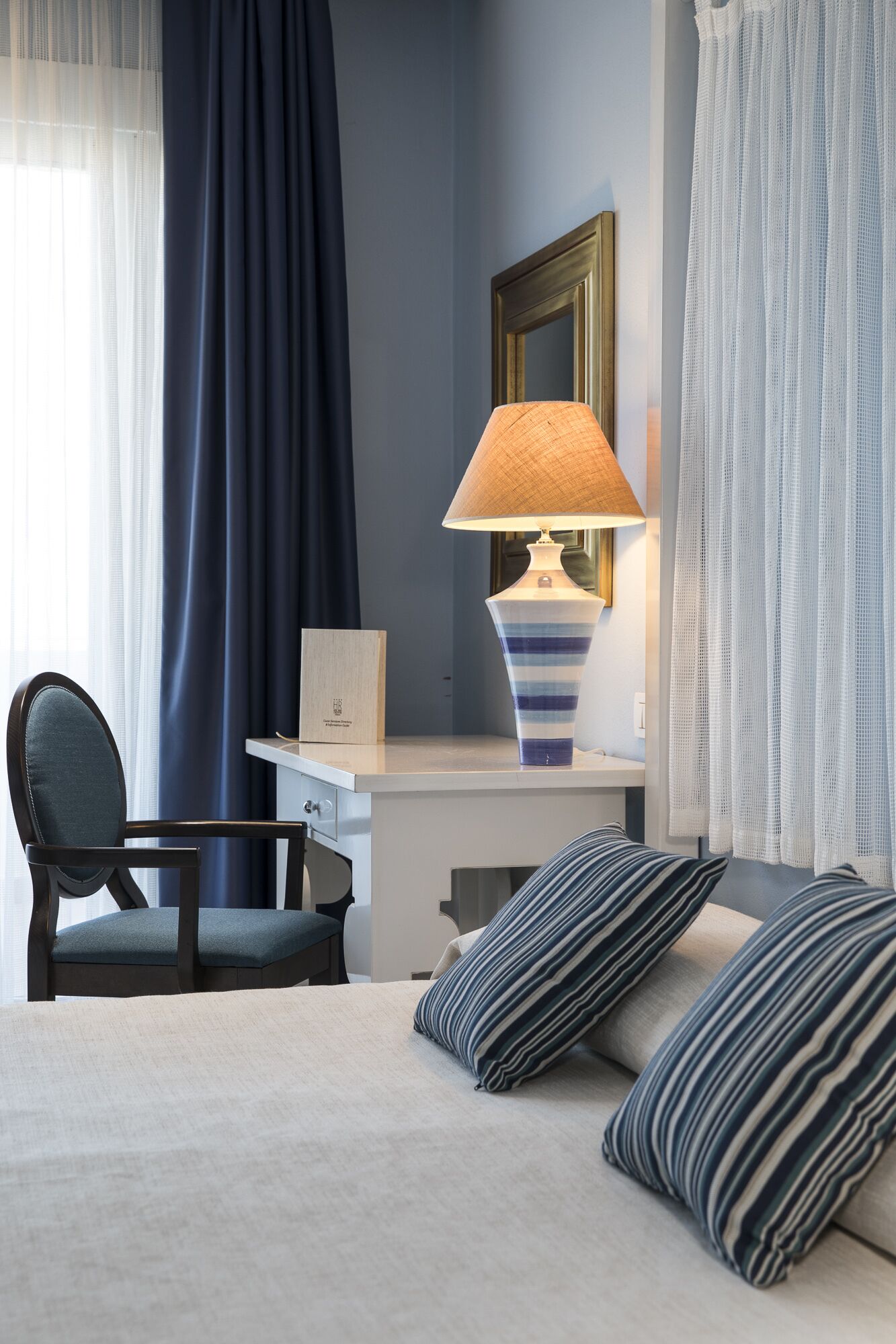 Ein Hotelzimmer mit Bett, Schreibtisch, Stuhl, Lampe und Spiegel.