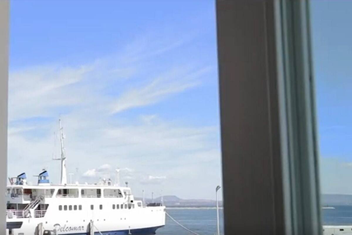 Blick aus dem Fenster auf ein weißes Boot, das in einer Marina liegt, mit blauem Himmel.