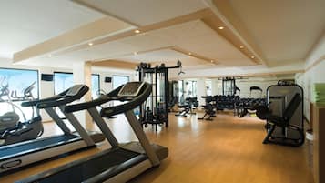 Un gimnasio con cintas de correr, máquinas de pesas y mancuernas.