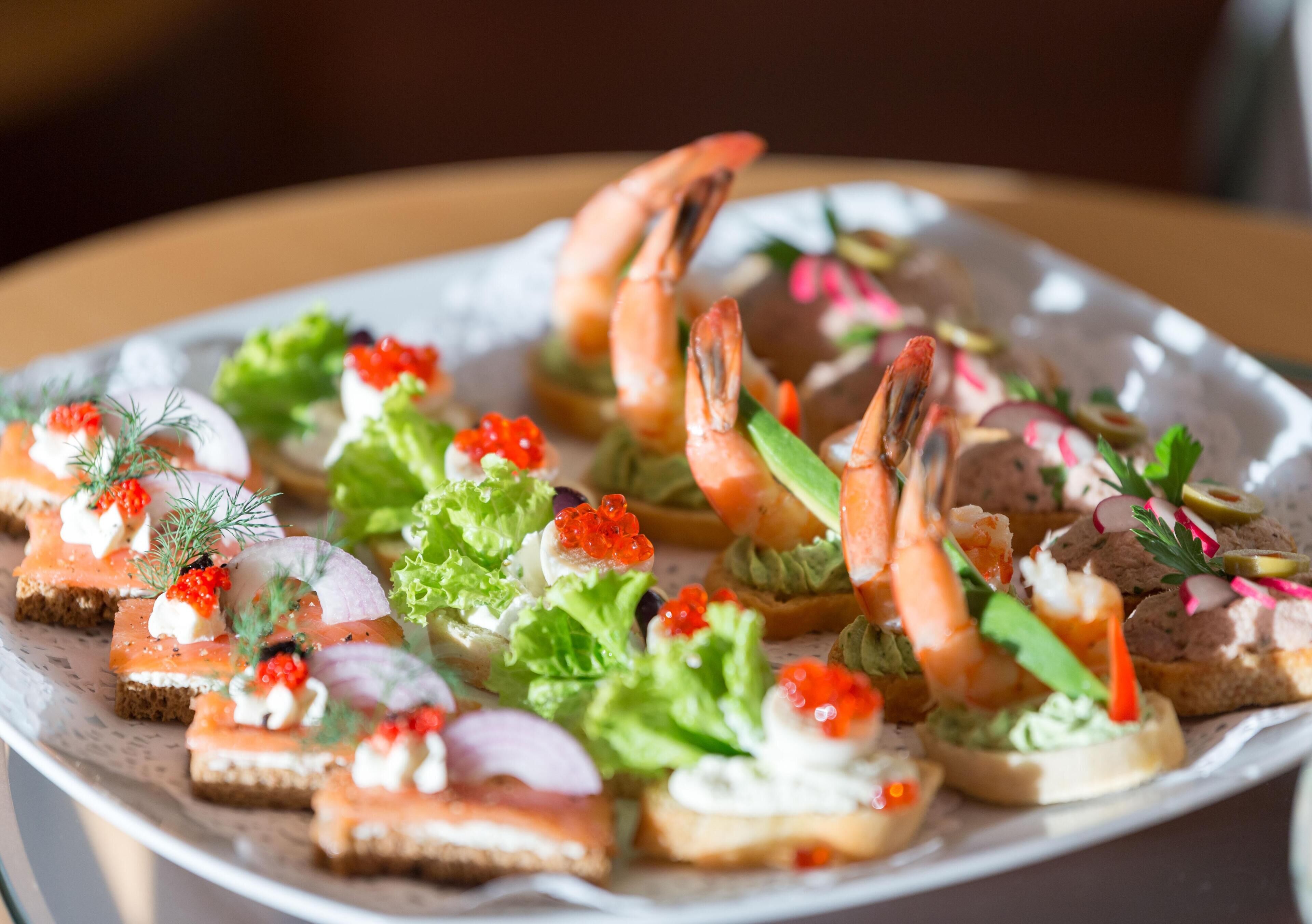 A platter of appetizers including shrimp, caviar, and various garnishes.