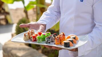 Una persona sostiene un plato blanco con diferentes piezas de sushi.