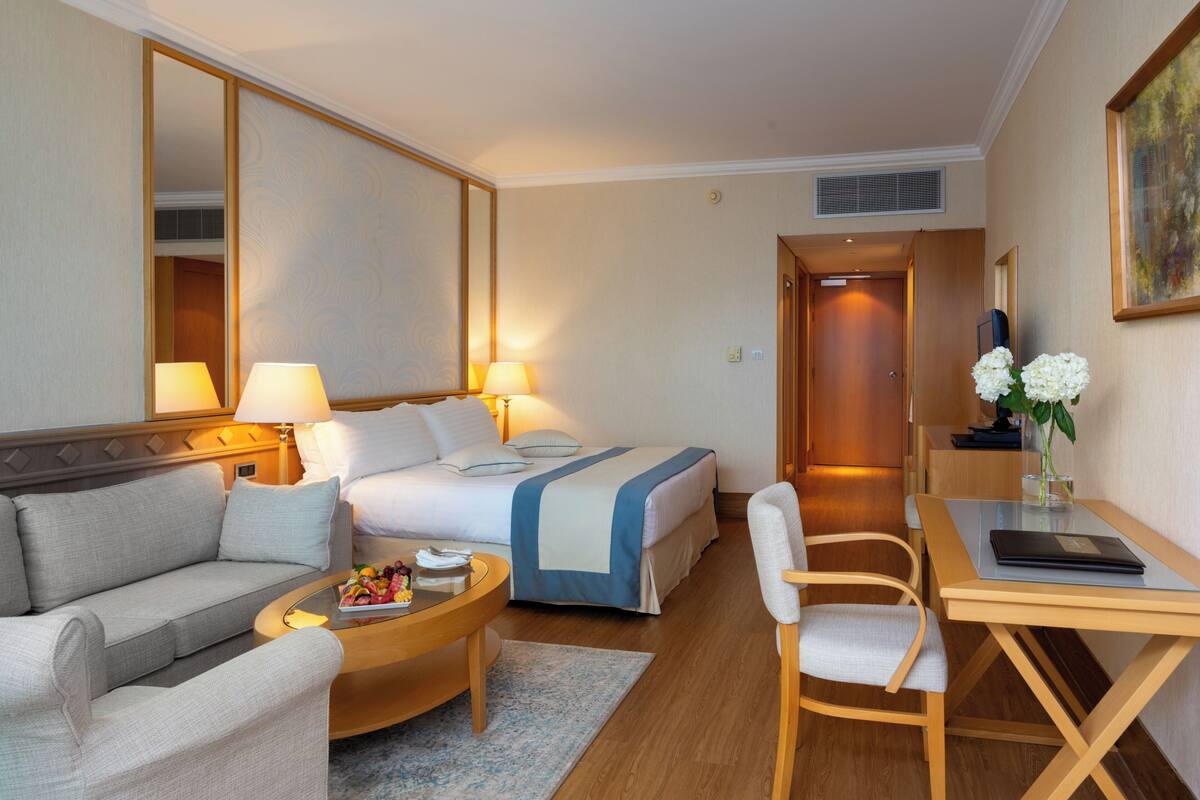 Hotellihuone, jossa on sänky, sohva, työpöytä ja tuoli.