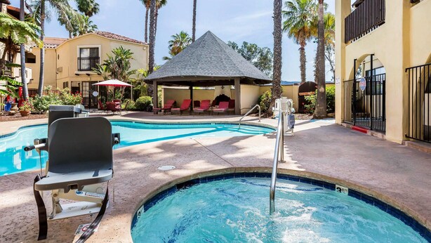 Un área de piscina con sillones de descanso y una zona de estar cubierta.