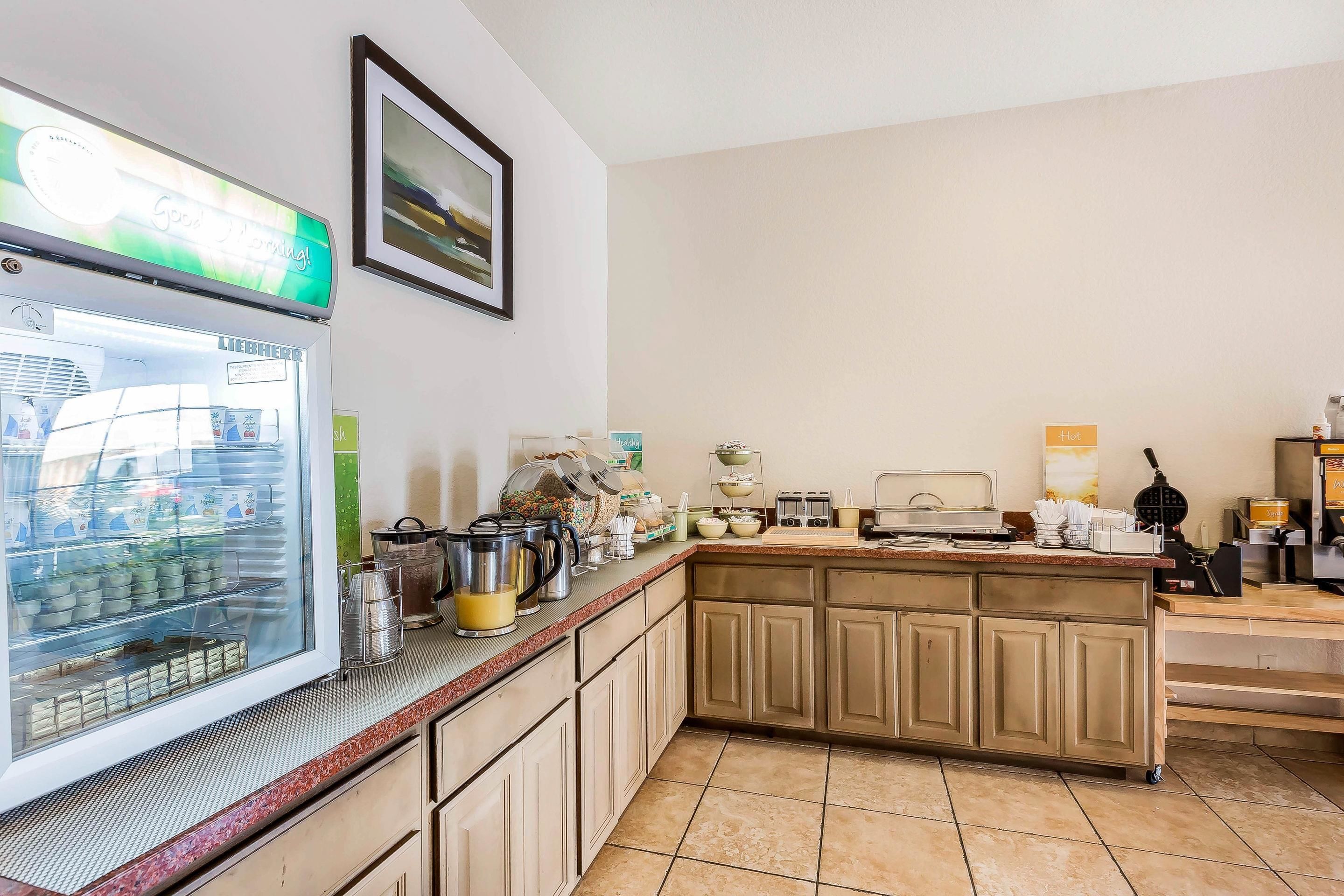 A kitchen with a refrigerator, coffee machine, and various kitchen appliances.