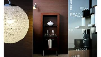 Una habitación con una lámpara de textura decorativa, un estante de madera con un florero y vasos, y una cafetera con la palabra "HERCOR".