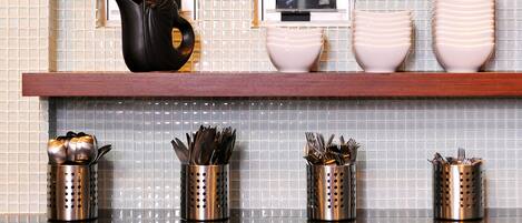 A kitchen counter with a black handbag, two white bowls, and four metal utensil holders.