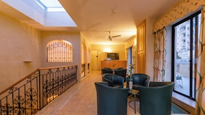 Um corredor amplo com escada, varanda com vista e um espaço de estar com cadeiras.