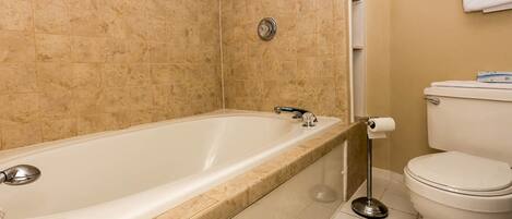 A bathroom with a bathtub, toilet, and a towel rack.