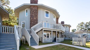 A two-story house with a covered porch, a staircase, and a fenced yard.