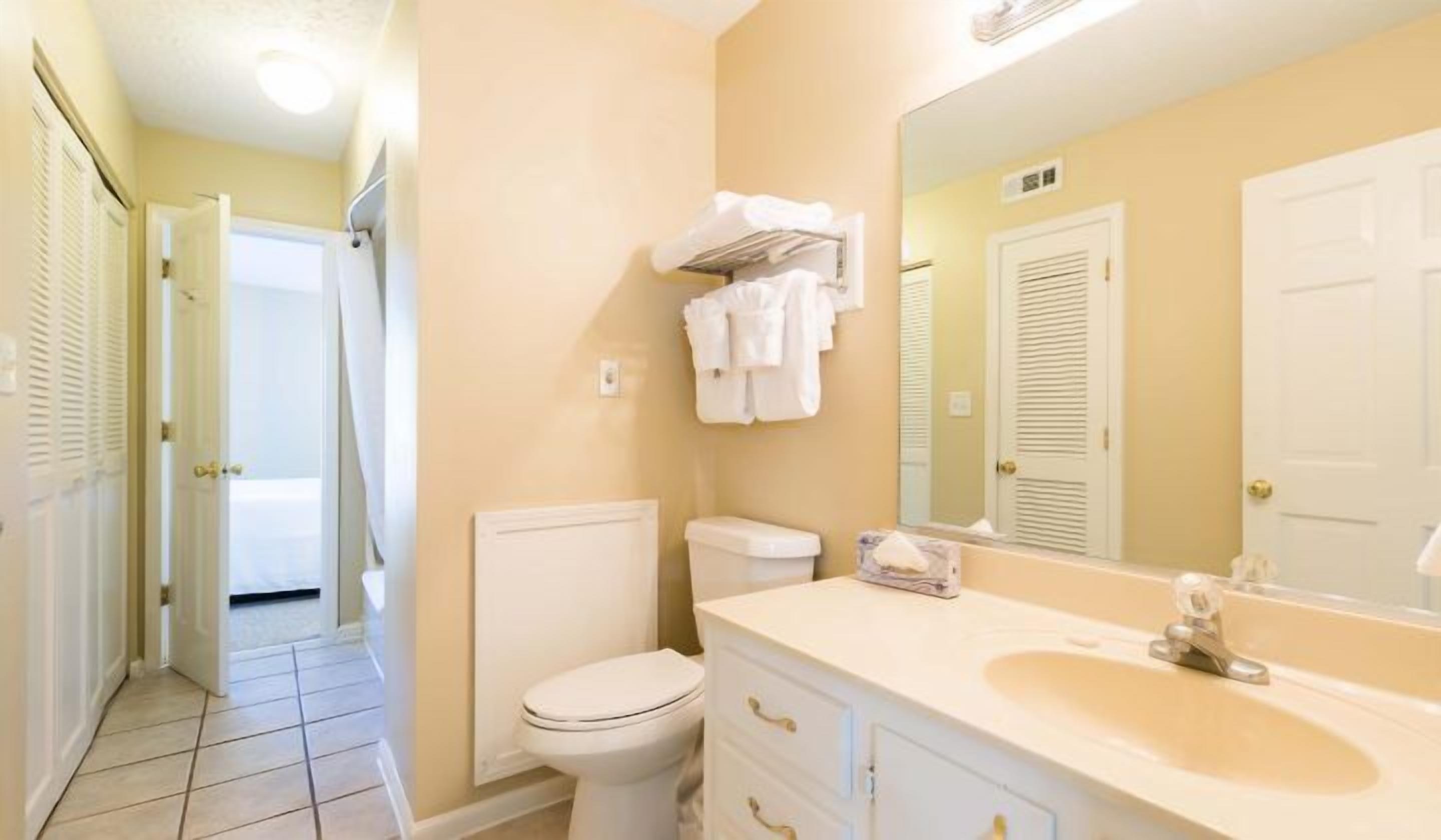 A bathroom with a toilet, a sink, a mirror, and a towel rack.