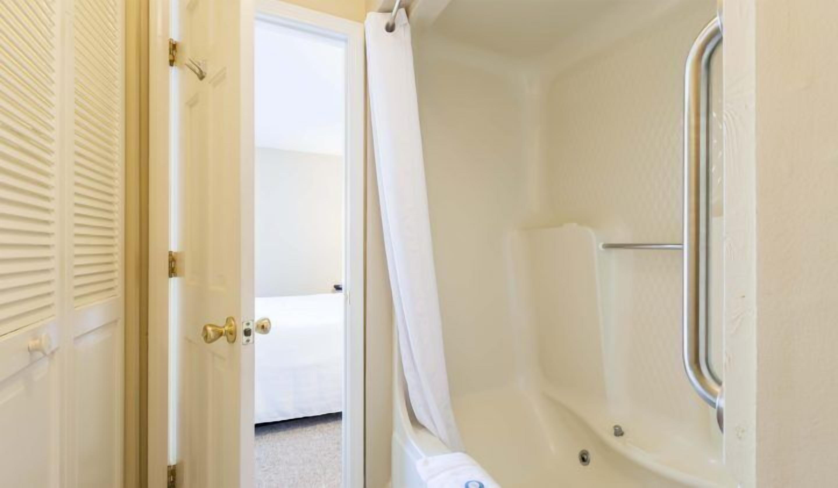 A small, enclosed bathroom with a shower area, a toilet, and a door leading to another room.