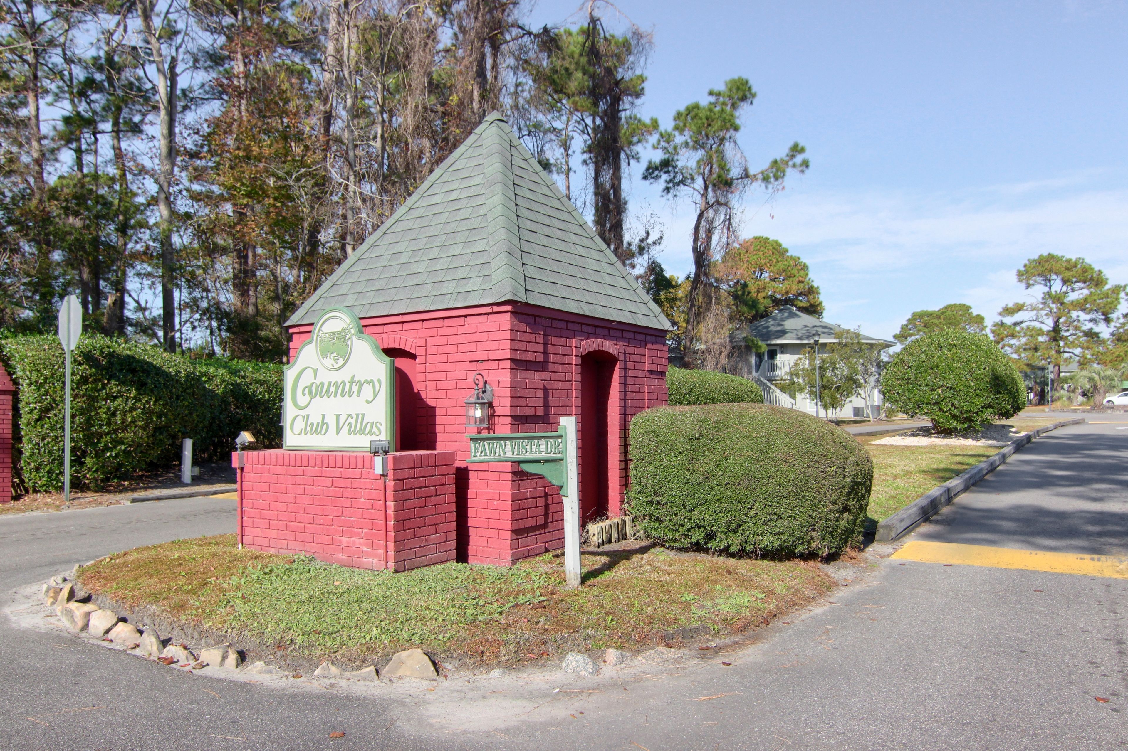 A red brick building with a green roof, labeled "Country Club Villas."