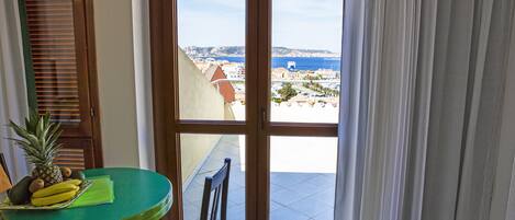 Ein Balkon mit Tisch, Stühlen und Blick auf das Meer und die Gebäude.