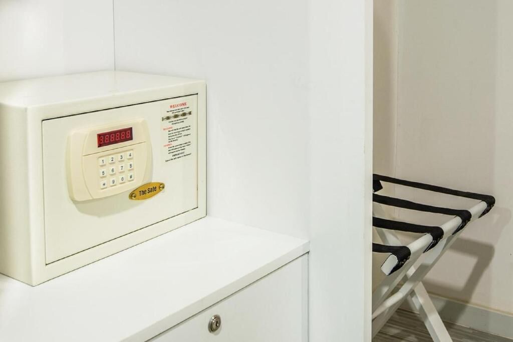 Pared blanca con una cerradura digital y una pequeña señal encima.