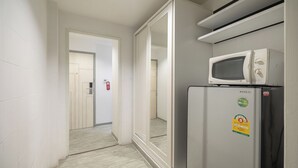 A narrow hallway with a sliding door leading to a room. A refrigerator with a microwave on top is visible on the right. - Pratunam City Inn (Bangkok)