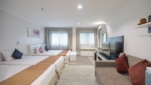 A hotel room with two beds, a sofa, a TV, and a desk. - Pratunam City Inn (Bangkok)