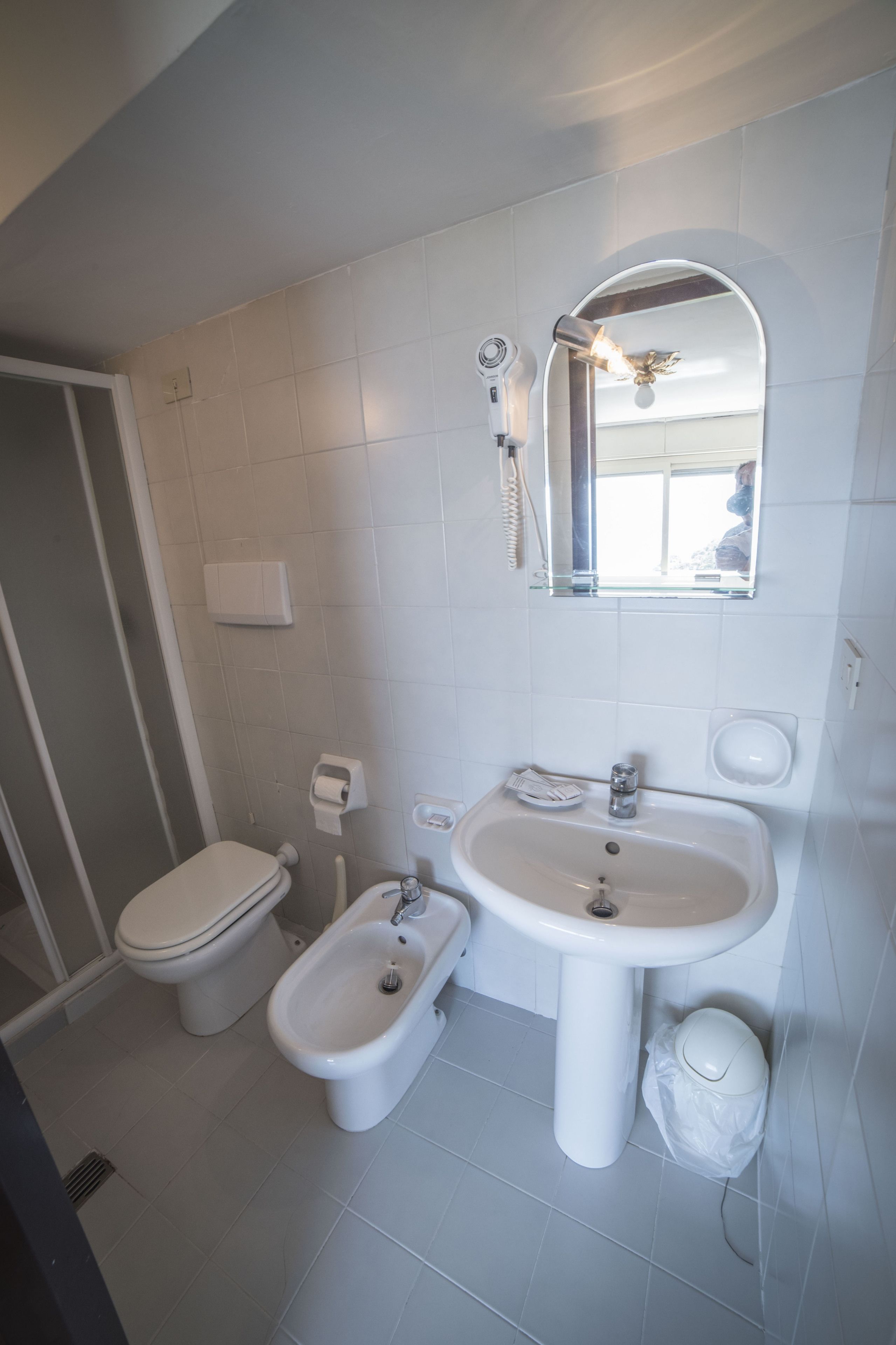 Een moderne badkamer met toilet, bidet, wastafel en spiegel.