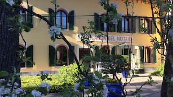 Un edificio amarillo con contraventanas verdes y un letrero que dice "CANDIDA DEL NOTAIO".