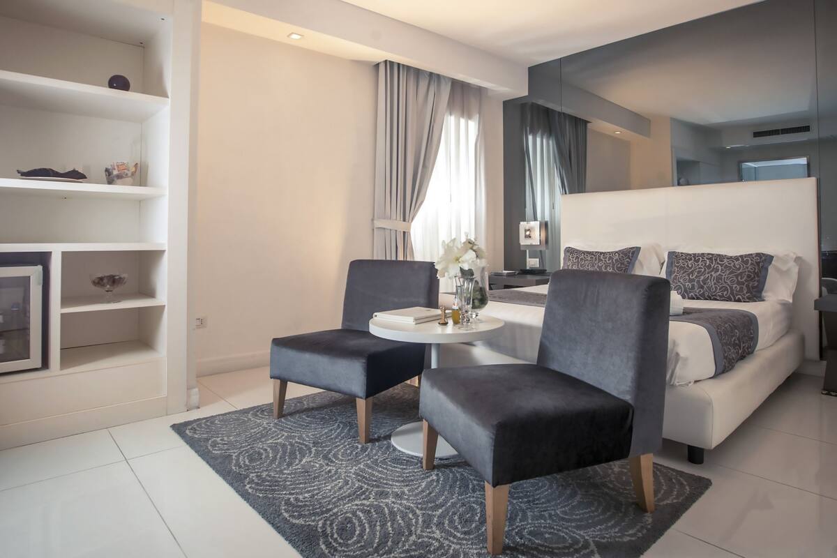 A modern living room with a sofa, two armchairs, a coffee table, and a TV.