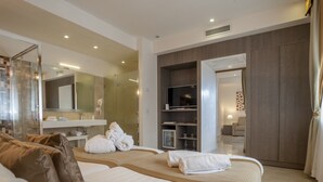Ein modernes Hotelzimmer mit zwei Betten, einem großen Spiegel, einem Fernseher und einem durchgegangenen Tür erkennbaren Badezimmer.
