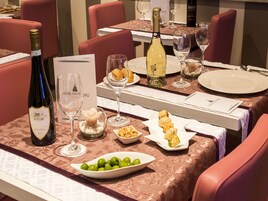 Een eettafel gedekt met wijnglazen, een fles wijn en schotels met hapjes.