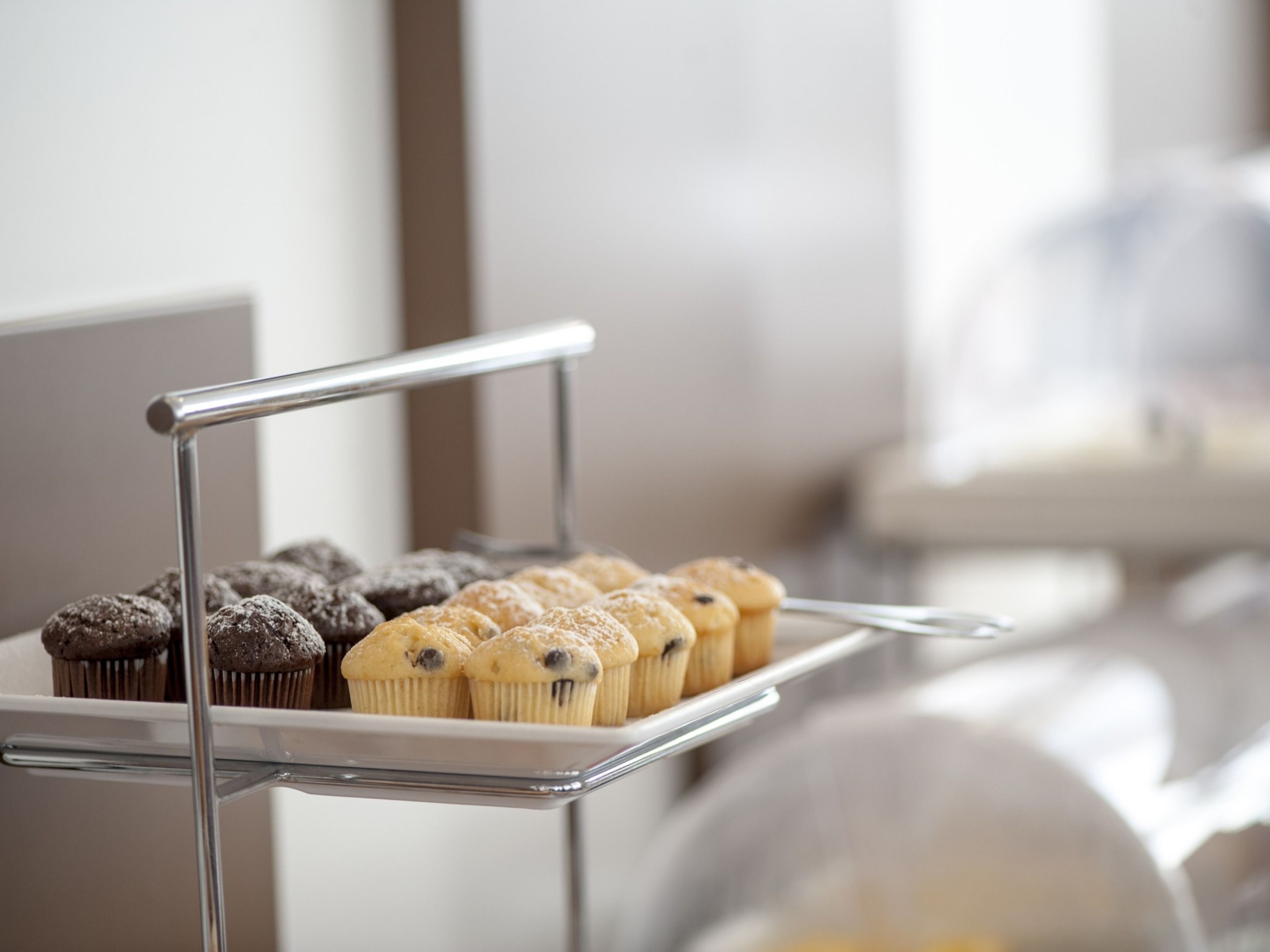 A metal rack with various muffins, some with chocolate frosting and others with a lighter topping.